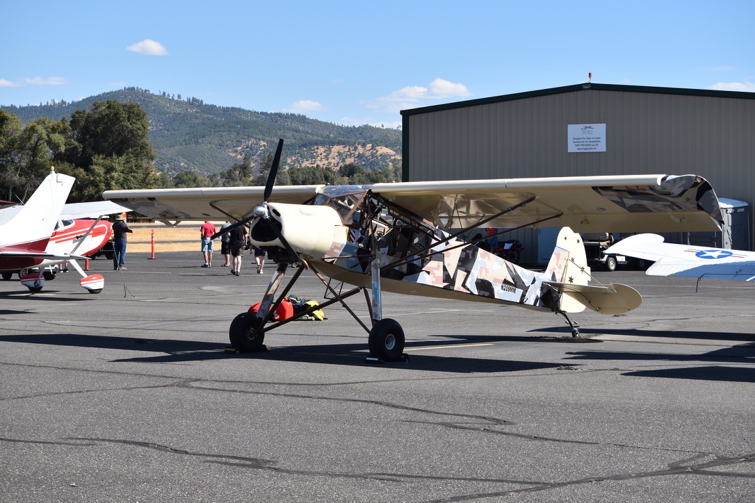 Slepcev Storch in camouflage paint scheme, side view at an airfield with hills in the background